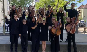 Junge deutsche Bands: Kinder und Jugendliche mit Streichinstrumenten, Flöten und Klarinetten posieren fröhlich für ein Foto.