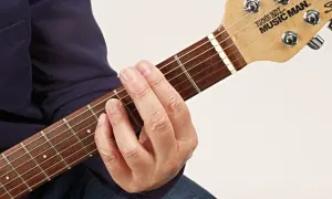 Gitarrenhals mit einem Finger, der einen Barre-Akkord greift. Der Zeigefinger liegt quer über alle Saiten.