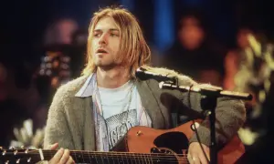Kurt Cobain spielt Akustikgitarre, ein ikonisches Bild, das an eine verstorbene Rockmusiker Liste erinnert.