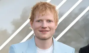 Ed Sheeran, der aus Halifax, England, stammt, lächelt in einem hellblauen Anzug.
