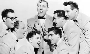 Gruppe von Männern in Anzügen und mit Fliegen, die singen.