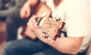 Nahaufnahme einer **bending Gitarre**, die von einer Person gespielt wird. Der Fokus liegt auf dem Hals und den Stimmmechaniken.