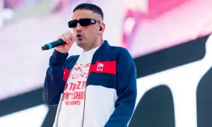 Der beste deutsche Rapper mit Mikrofon auf der Bühne, trägt Sonnenbrille und Bomberjacke.