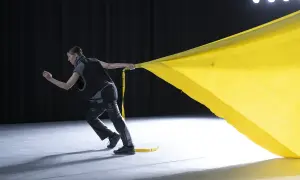 Tänzerin zieht ein gelbes Tuch, das sich wie ein Segel im Wind kräuselt. Perfekt für gute Lieder zum Tanzen Choreographie.