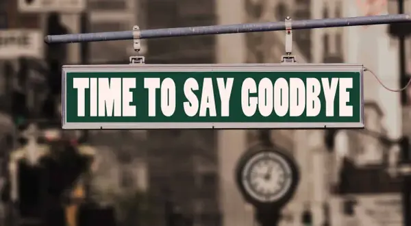 Ein Schild mit der Aufschrift "TIME TO SAY GOODBYE" hängt über einer Straße. Es ist Zeit für einen **Lied Abschied**.
