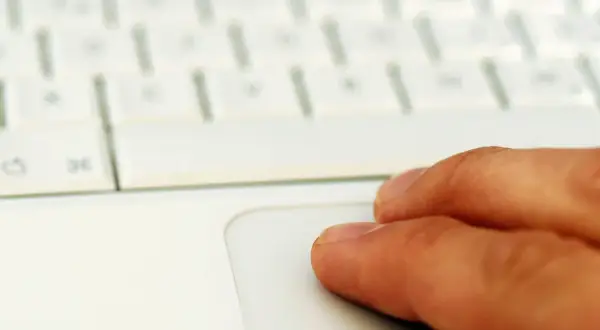 Finger auf einem weißen Laptop-Touchpad. Suche nach professionelle midifiles kostenlos für dein nächstes Musikprojekt.
