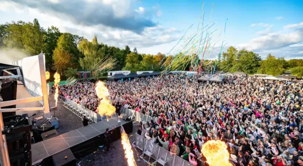 Große Menschenmenge feiert bei einem Konzert mit Flammenwerfern und Konfetti. Die "Malle Hits" bringen die Stimmung zum Kochen.
