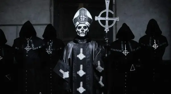 Geister-Frontmann mit Totenkopf-Make-up und Kapuzengewänder, die an beliebte Metal-Bands erinnern.