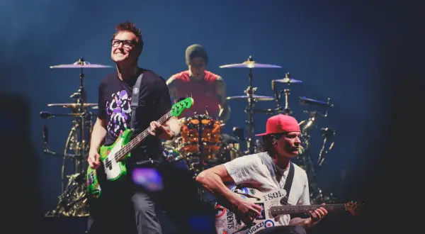 Blink 182 heute: Mark Hoppus spielt Bass, Travis Barker am Schlagzeug, Tom DeLonge mit Gitarre. Energiegeladener Auftritt!