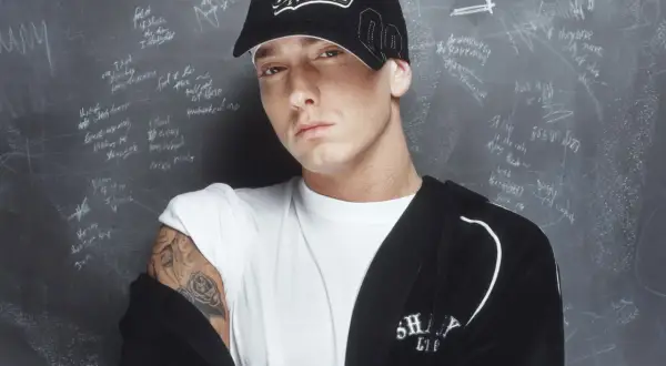 Eminem, der erfolgreichste Rapper, trägt eine "Shady"-Kappe vor einer Tafel mit Formeln und Texten.