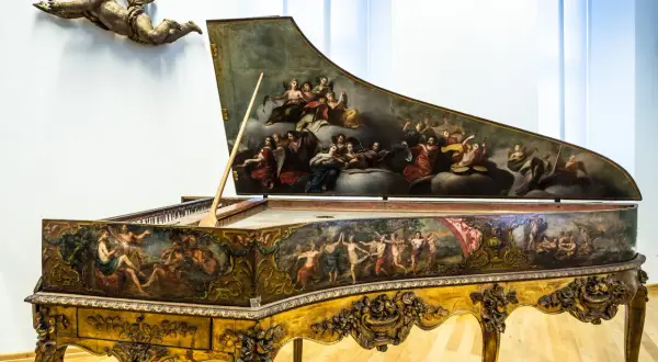 Ein prachtvolles Cembalo, verziert mit barocken Malereien, wie sie Johann Sebastian Bach liebte. Ein geflügelter Putto schwebt darüber.