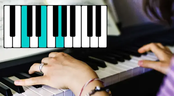 Hände spielen am Klavier einen Akkord. Die blauen Tasten zeigen die Noten für einen C-Dur-Akkord.