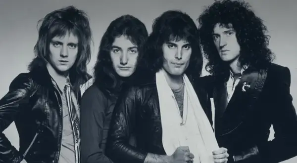 Die Mitglieder von Queen posieren für ein Schwarz-Weiß-Foto. Von links nach rechts: Roger Taylor, John Deacon, Freddie Mercury und Brian May.