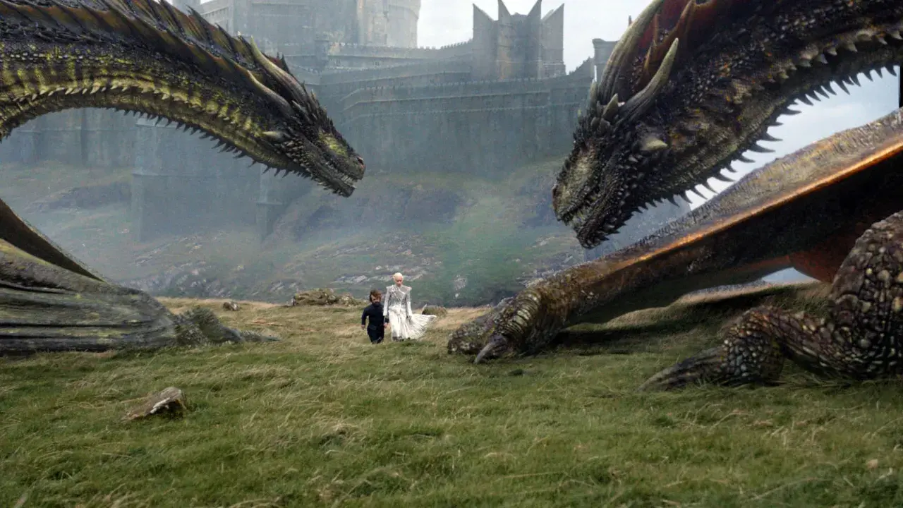 Zwei Drachen blicken sich gegenüber, während Daenerys und Tyrion im Gras stehen. Die epische **Titelmusik Game of Thrones** beginnt.