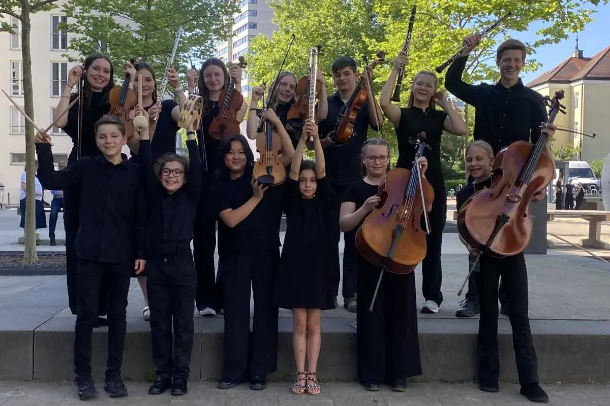 Junge deutsche Bands: Kinder und Jugendliche mit Streichinstrumenten, Flöten und Klarinetten posieren fröhlich für ein Foto.