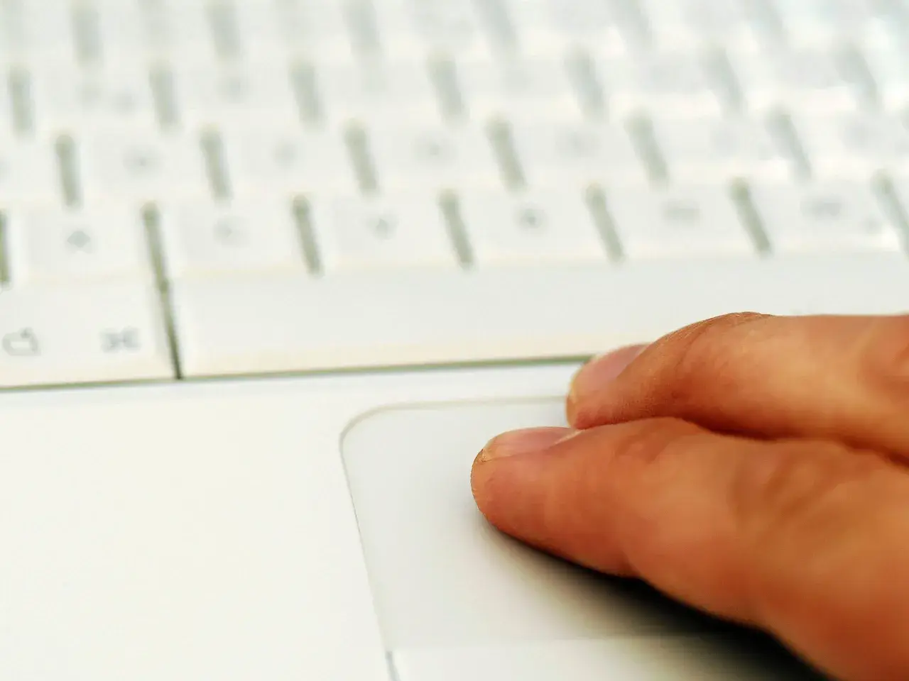 Finger auf einem weißen Laptop-Touchpad. Suche nach professionelle midifiles kostenlos für dein nächstes Musikprojekt.