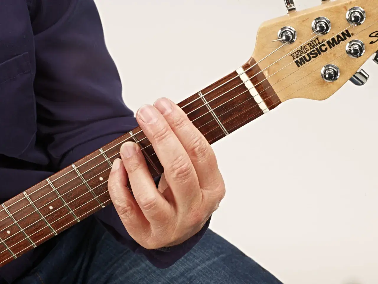 Gitarrenhals mit einem Finger, der einen Barre-Akkord greift. Der Zeigefinger liegt quer über alle Saiten.