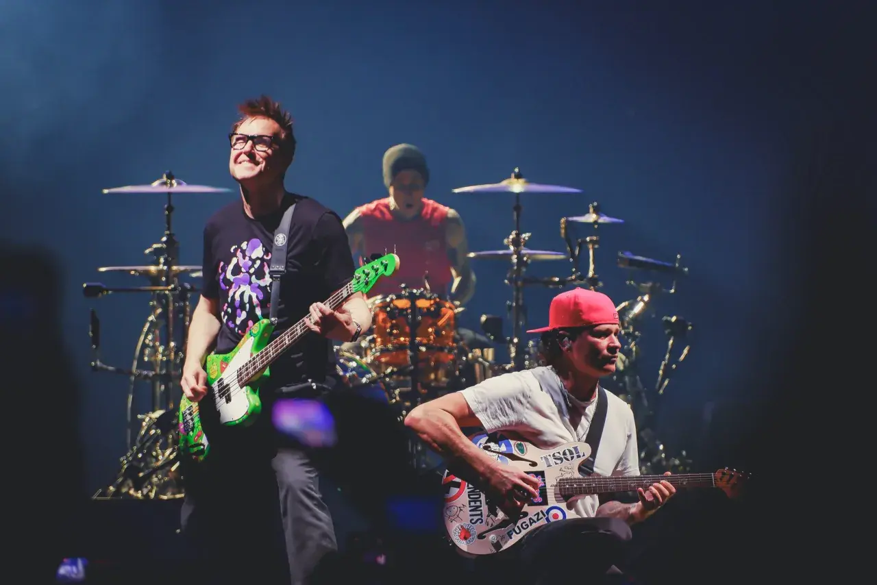 Blink 182 heute: Mark Hoppus spielt Bass, Travis Barker am Schlagzeug, Tom DeLonge mit Gitarre. Energiegeladener Auftritt!