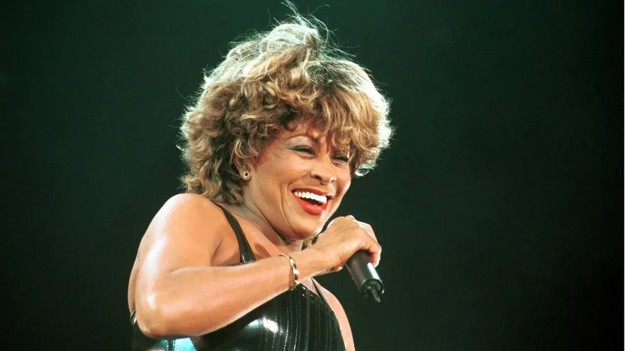 Tina Turner lacht und singt ins Mikrofon, eine Ikone, die mit ihrem erfolgreichsten Song aller Zeiten die Massen begeistert.