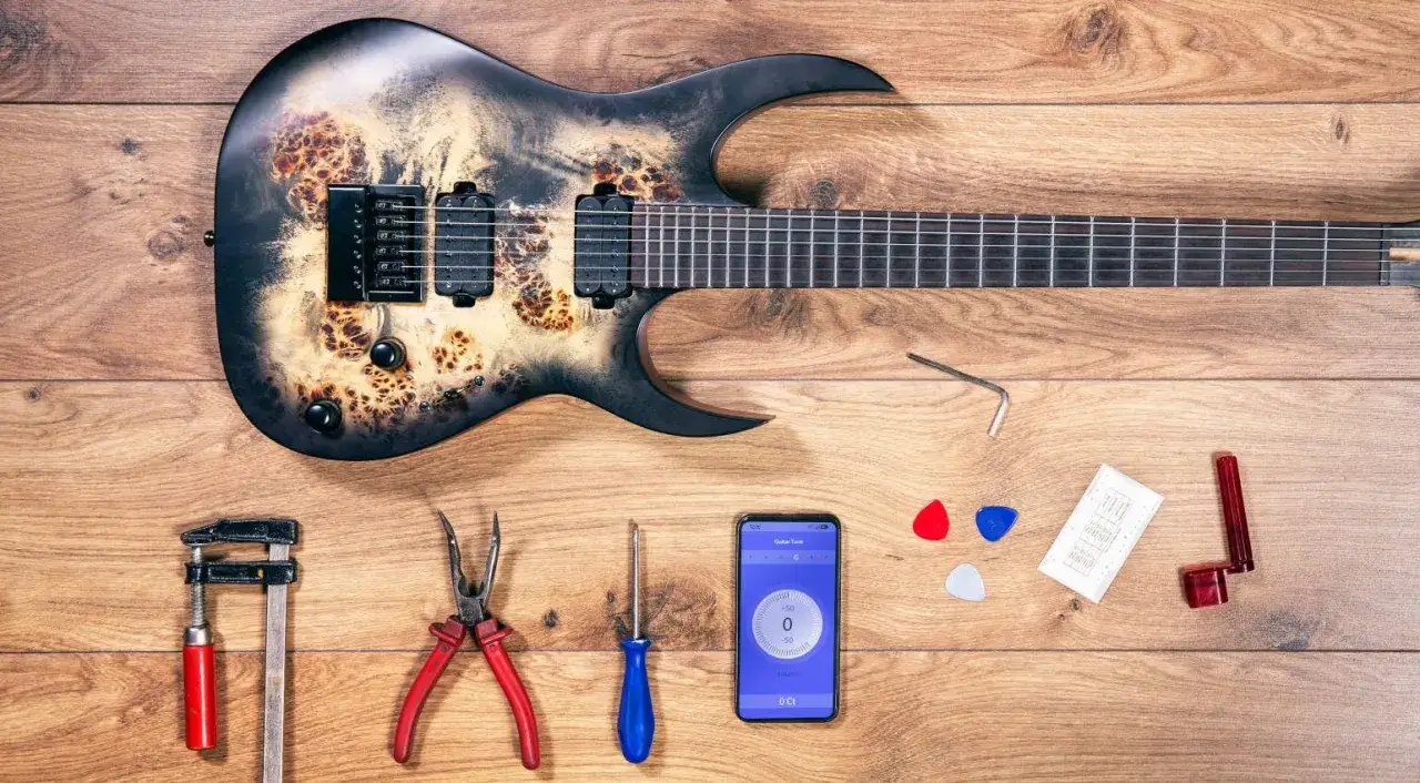 Schwarze E-Gitarre mit auffälliger Maserung, Werkzeug und Handy-App zum Gitarre einstellen bereitgelegt.