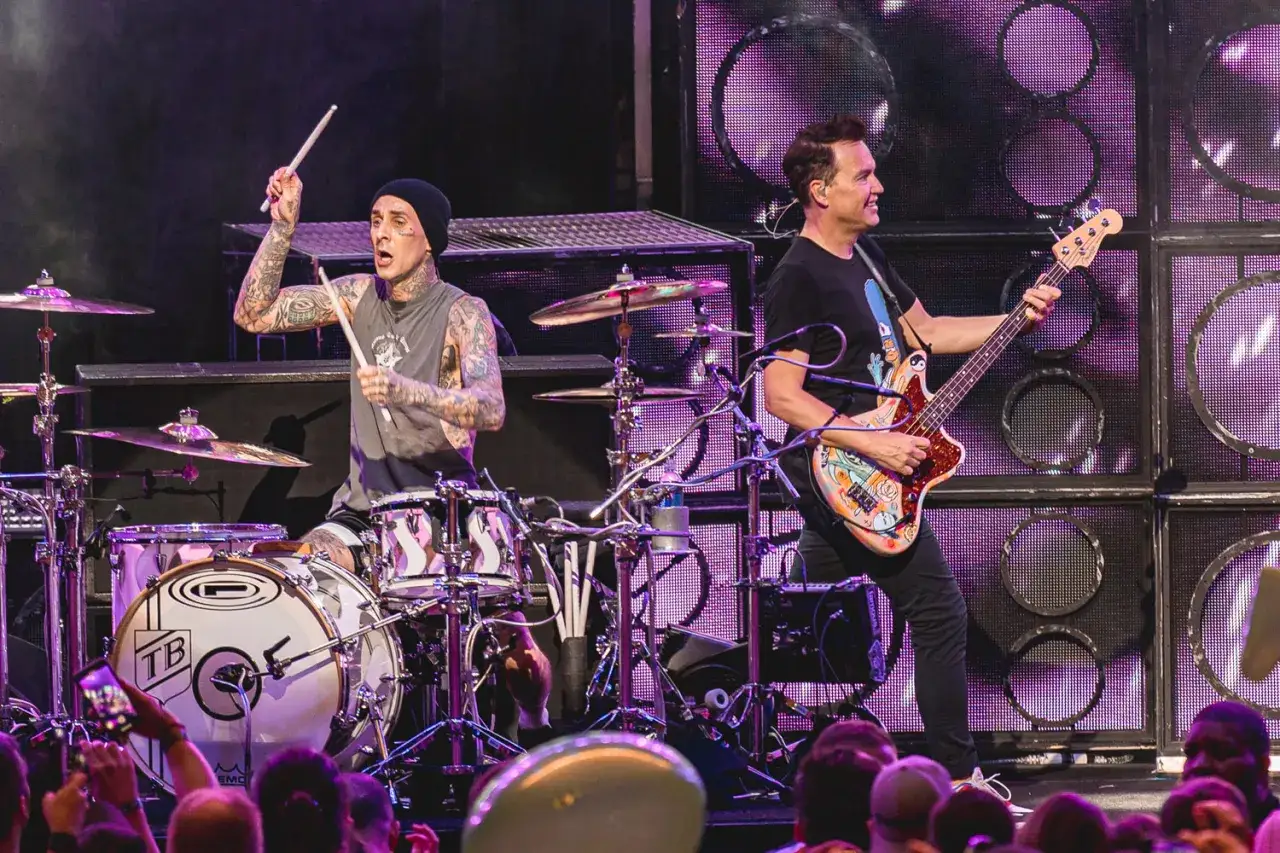 Travis Barker trommelt energisch, w&auml;hrend Mark Hoppus mit seiner bunten Bassgitarre die B&uuml;hne rockt. Mitglieder von blink-182 live in Aktion.