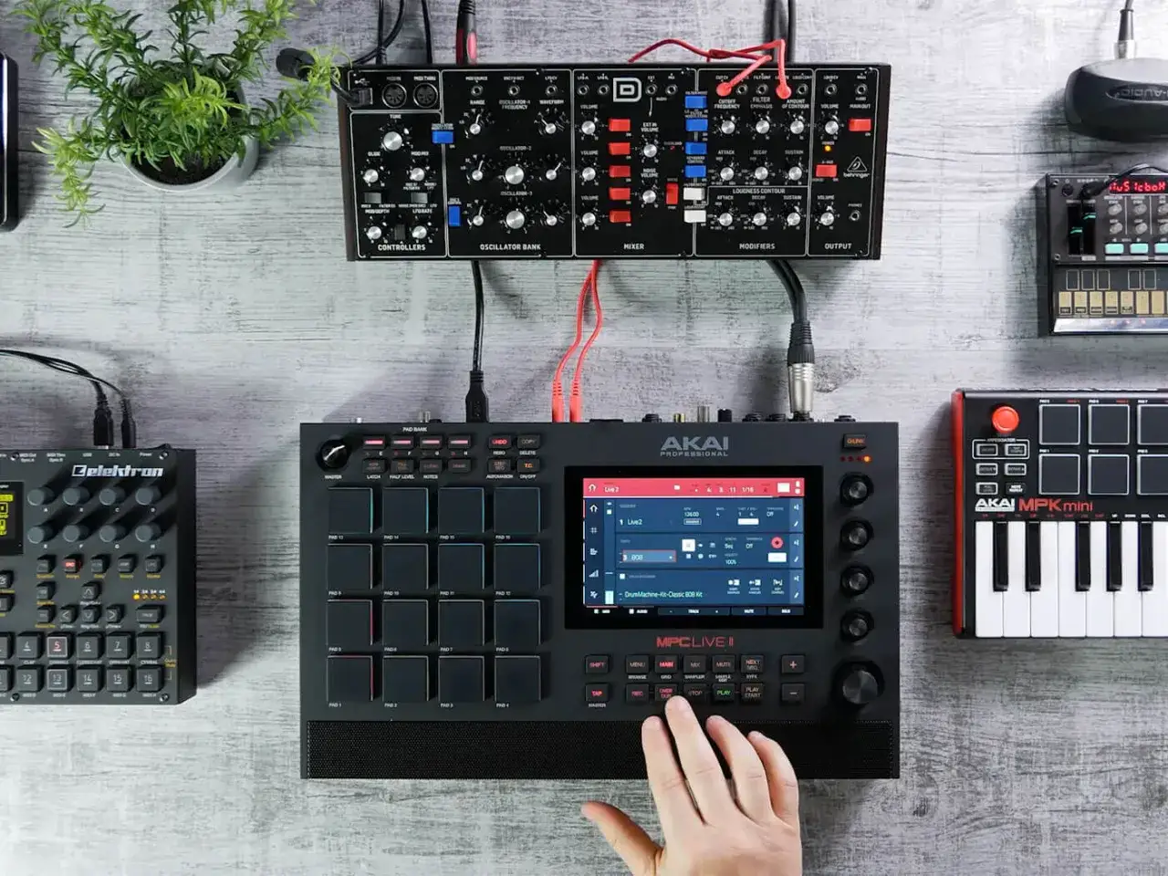 MPC Live II mit Pads und Touchscreen, daneben ein kleinerer MIDI-Controller und ein Modular-Synthesizer.