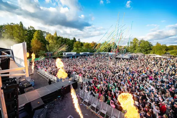 Große Menschenmenge feiert bei einem Konzert mit Flammenwerfern und Konfetti. Die "Malle Hits" bringen die Stimmung zum Kochen.